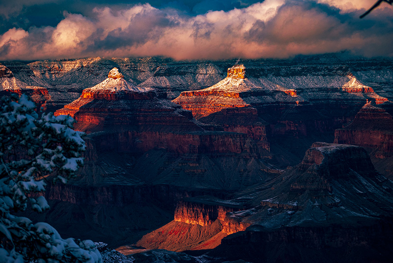 Soft evening light illuminates snow-capped spires inside Grand Canyon